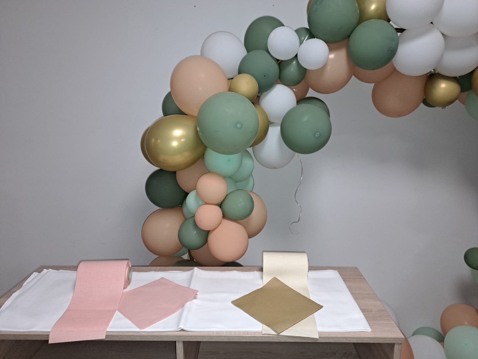 Ballongirlande in Salbeigruen und Gold ueber dem Geschenktisch