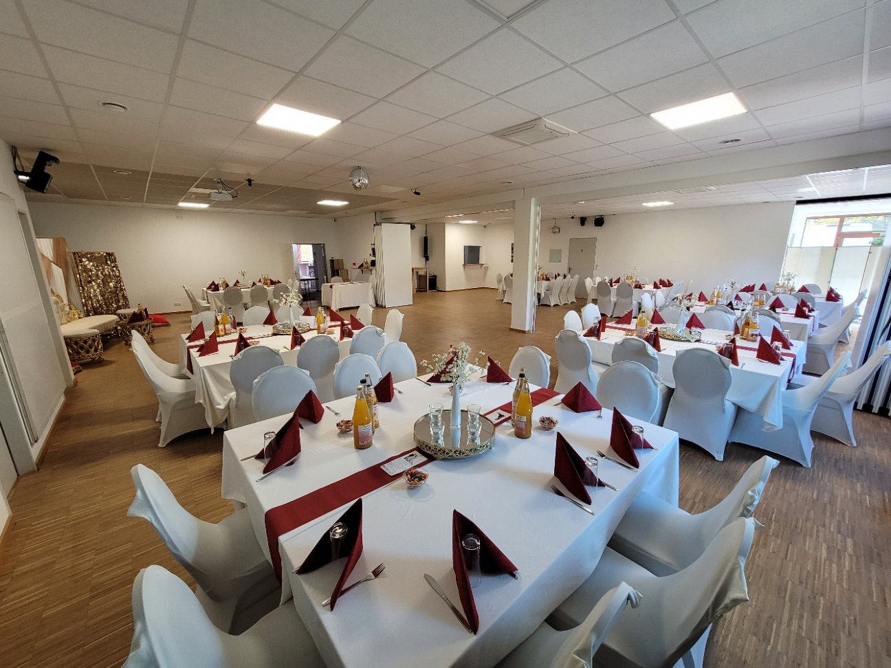 Runde Hochzeitstische mit Stuhlhussen und Blumenschmuck im Festsaal