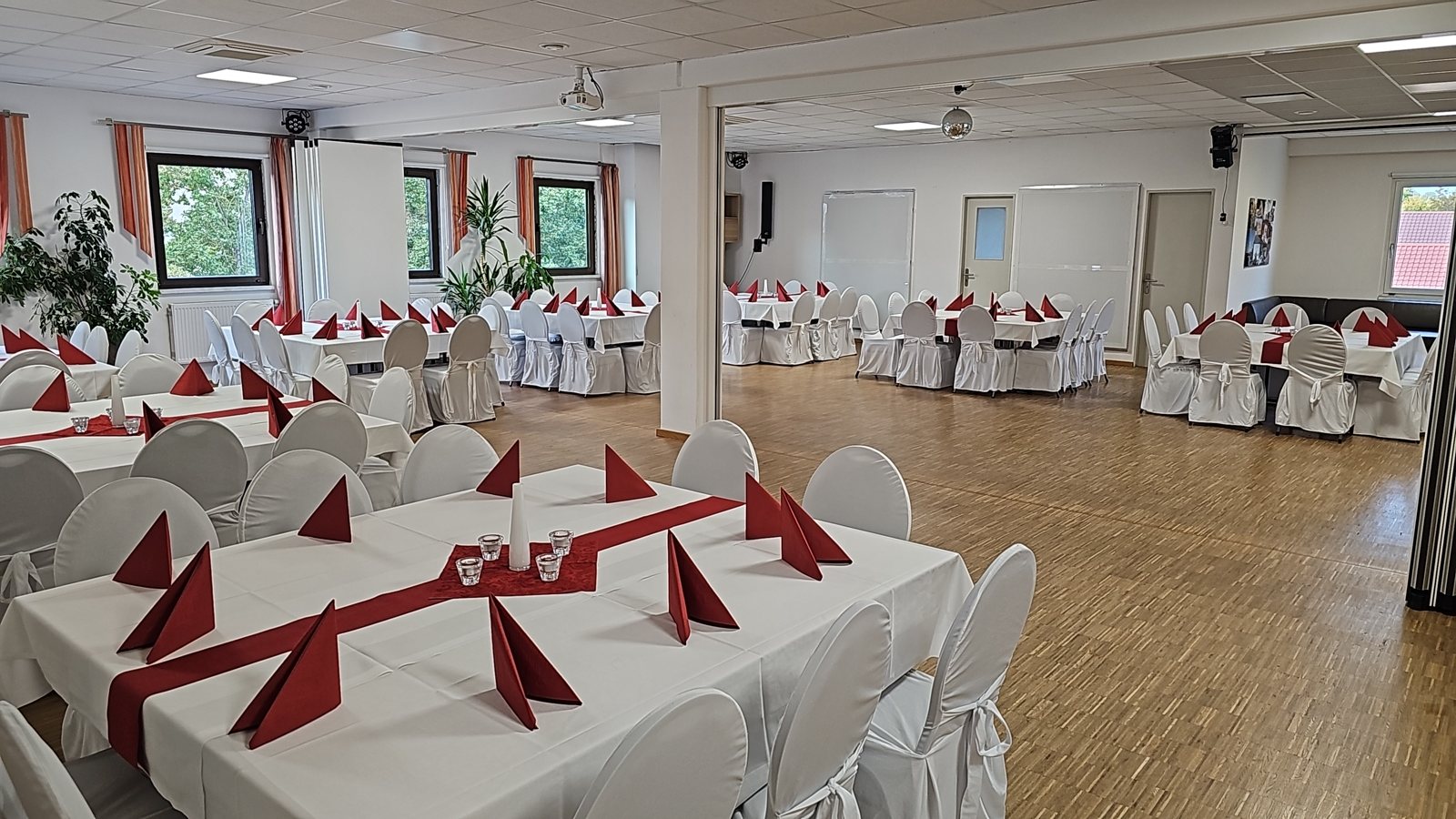 Runde Tische mit weissen Stuhlhussen im Festsaal, festlich eingedeckt