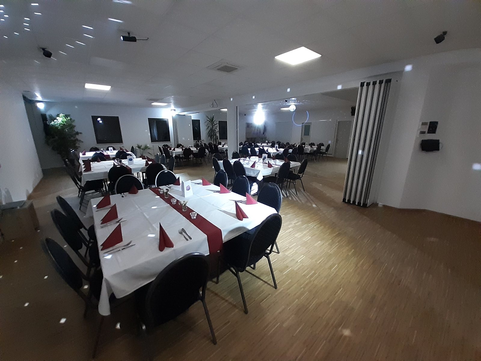 Lange Tafel im Festsaal mit weissen Tischdecken und weinroten Servietten
