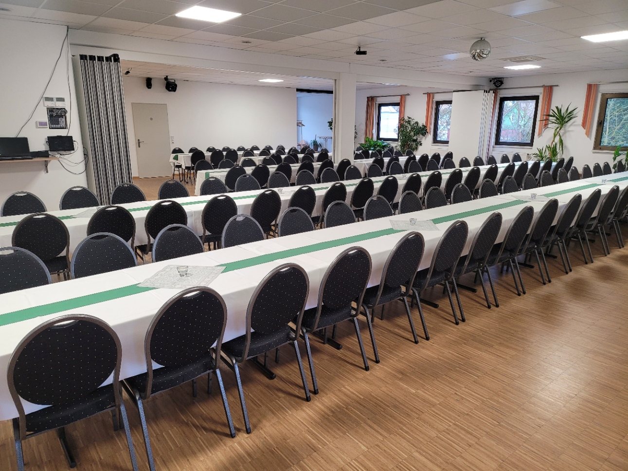 Festsaal in Tafelbestuhlung mit gruenen Tischlaeufern fuer eine grosse Feier
