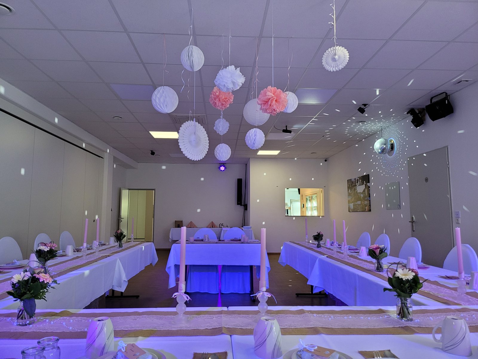 Saal links in blauer Beleuchtung mit U-foermiger Tafel und Papierlampions