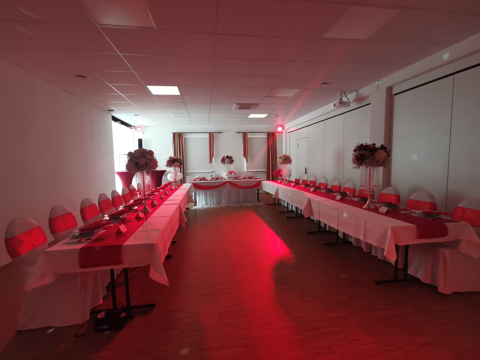 Saal links festlich in Rosa und Weiss dekoriert mit Blumengestecken