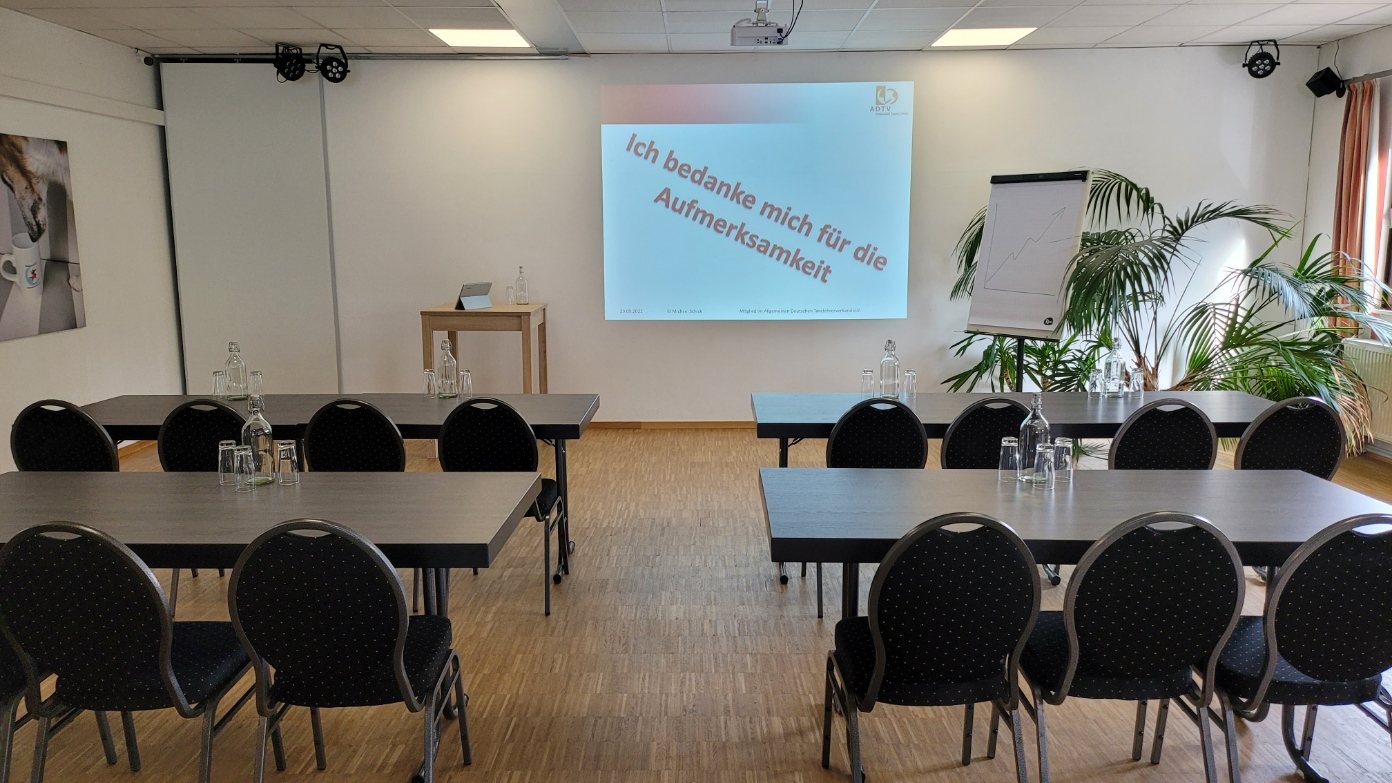 Tagungsraum mit Beamer, Leinwand und parlamentarischer Bestuhlung